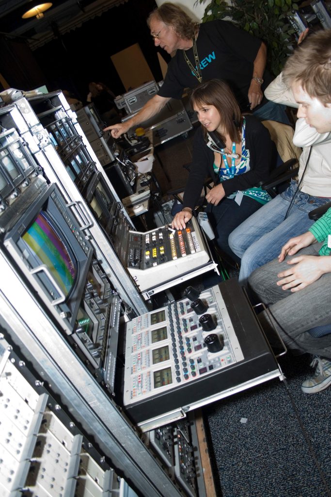 Two young people working at an old school broadcasting vision mixer
